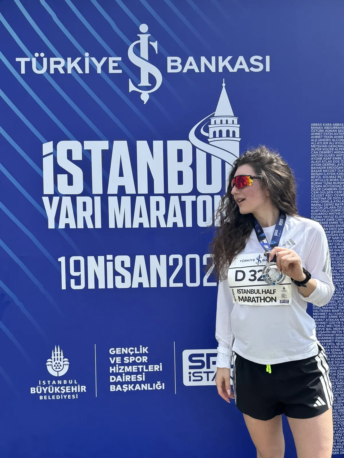 Yana with a finisher medal in front of the Istanbul Half Marathon wall